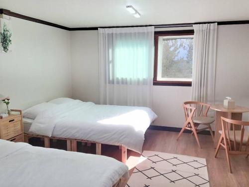 a bedroom with two beds and a table and a window at Stay Mellow in Seoul