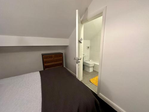 a bedroom with a bed and a bathroom with a toilet at Waterside 4BR Townhouse Stretford, FREE Parking in Manchester