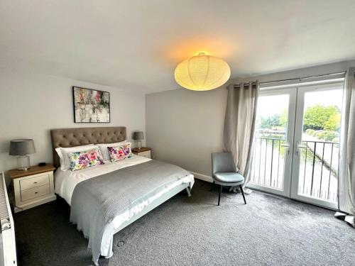 a bedroom with a bed and a chair and a window at Waterside 4BR Townhouse Stretford, FREE Parking in Manchester