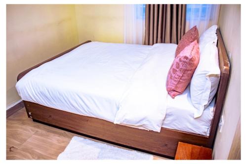 a bed with white sheets and two pillows on it at Nyatana suite (Fully furnished apartments) in Narok