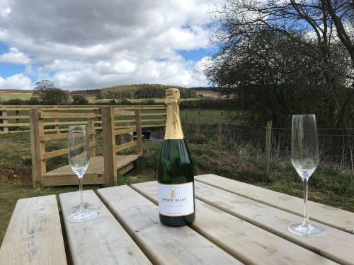 a bottle of wine and two glasses on a wooden table at Robins Rest in the North York Moors in Rosedale Abbey