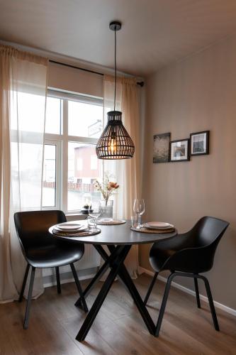 a dining room with a table and chairs and a lamp at Ray of Sunshine Hafnargata in Keflavík