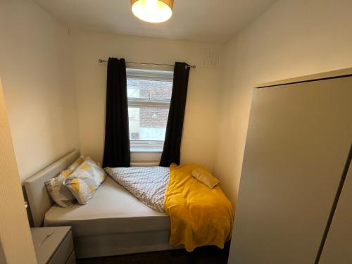 a small bedroom with a bed with a window at Super Value Three Bedroom House in Hull