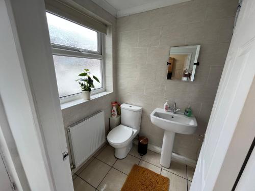 a bathroom with a toilet and a sink and a window at Super Value Three Bedroom House in Hull