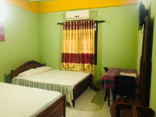 a small room with two beds and a table at River Garden Hotel Anuradhapura in Anuradhapura