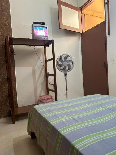 a room with a bed and a tv on a shelf at Pouso D' Braga in Pirenópolis