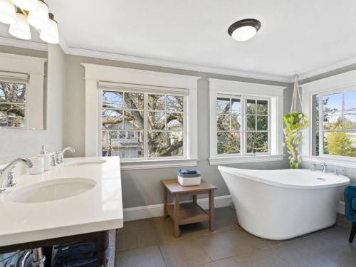 uma casa de banho com 2 lavatórios, uma banheira e janelas em Vintage-Modern Craftsman Home Near Alberta Arts em Portland