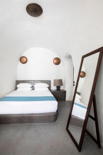 a bedroom with a bed and a mirror at Ducato di Oia - Adults Only in Oia