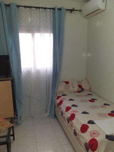 a bedroom with a bed and a window with blue curtains at KEUR AMINATA in Dakar