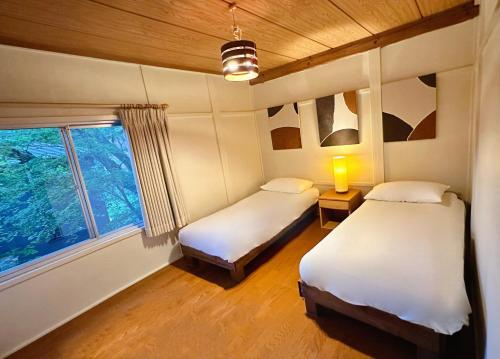 two beds in a room with a window at Snowood Chalet Hakuba in Hakuba
