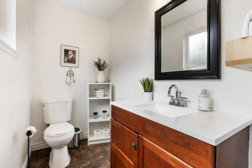 La salle de bains est pourvue d'un lavabo, de toilettes et d'un miroir. dans l'établissement Vancouver Escape, Spacious 3-Bdrm Private Home, à Vancouver