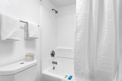 baño blanco con ducha y lavamanos en Qubed San Antonio, en San Antonio