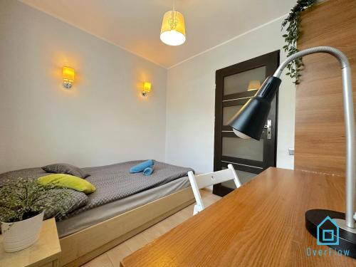 a bedroom with a bed and a desk with a lamp at Cheerful Room in Gdańsk