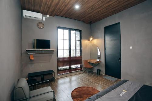 1 dormitorio con cama, escritorio y ventana en Emerald Guest House London Purwokerto en Purwokerto
