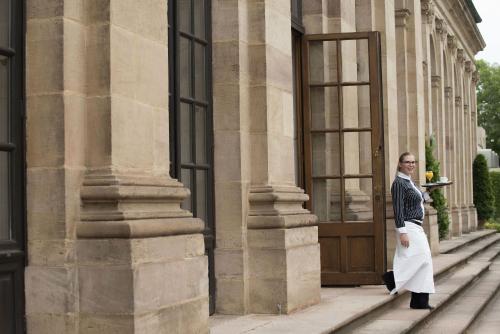 a man standing in front of a building with a door at Maritim Hotel Am Schlossgarten in Fulda