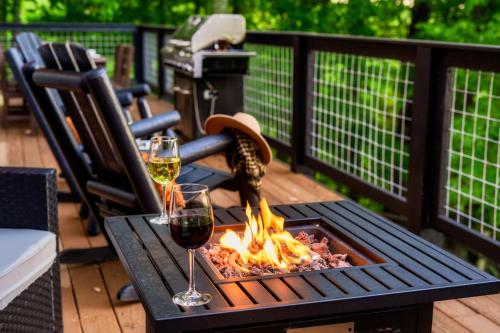 a fire pit on a deck with two glasses of wine at Woodhaven - Private - 3 Suites - Gorgeous Views - 3 Pools - GameRm - HotTub - Lots of Bears in Gatlinburg