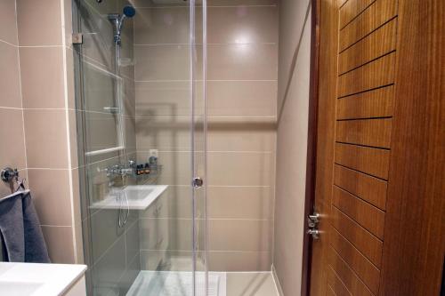 una ducha con una puerta de cristal junto a un lavabo en Nice Apartment close to Casablanca Airport, en Nouaceur