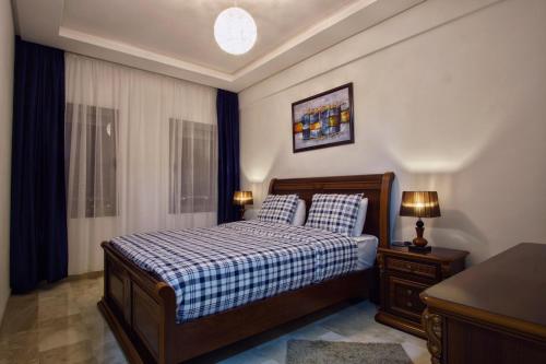 1 dormitorio con 1 cama con una manta azul y blanca a cuadros en Nice Apartment close to Casablanca Airport, en Nouaceur