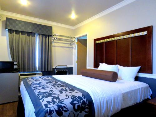 a hotel room with a large bed with a large headboard at La Bonita Inn Motel in Long Beach