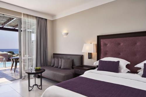 a hotel room with a bed and a couch at Atlantica Belvedere Resort - Adults Only in Kardamaina