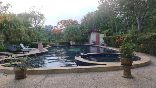 una piscina en un patio con 2 sillas y plantas en Beautiful bungalow with a communal outdoor pool and 2 km from the sandy beach, en Ban Sa