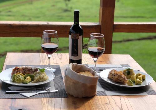 a table with two plates of food and wine glasses at ECOLODGE PIEDRA Y AGUA in El Soberbio