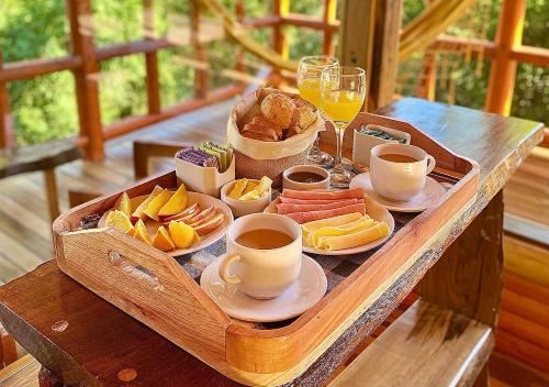 a tray of breakfast foods and drinks on a wooden table at ECOLODGE PIEDRA Y AGUA in El Soberbio