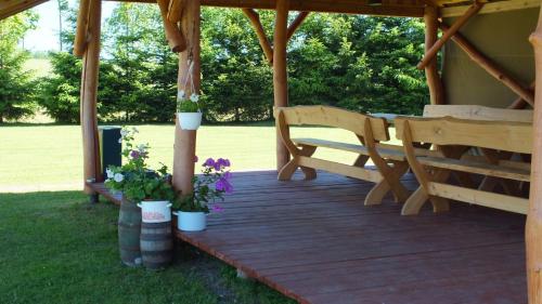 eine Holzveranda mit einem Pavillon mit zwei Bänken und Blumen in der Unterkunft Sodyba PEIZAŽAS in Kirdeikiai