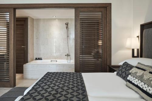 a bedroom with a large bed and a bath tub at Atlantica Belvedere Resort - Adults Only in Kardamaina