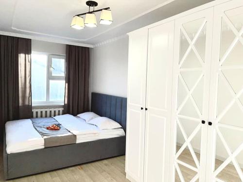 ein Schlafzimmer mit einem Bett und einem großen weißen Schrank in der Unterkunft Квартира в самом центре in Qaraghandy