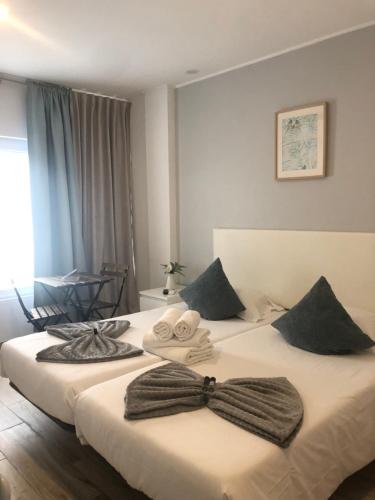 een hotelkamer met twee bedden met bogen erop bij Calmaria Guesthouse in Porto Covo