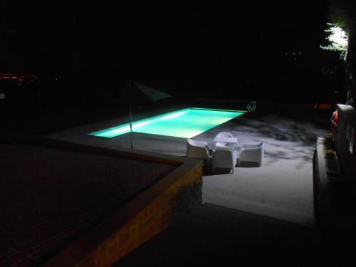 a swimming pool at night with two chairs around it at Casa da Torre in Pico