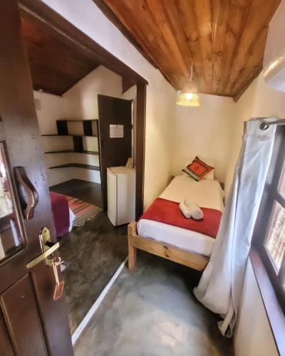 a small bedroom with a bed and a door at Pousada Raiz Forte in Caraíva