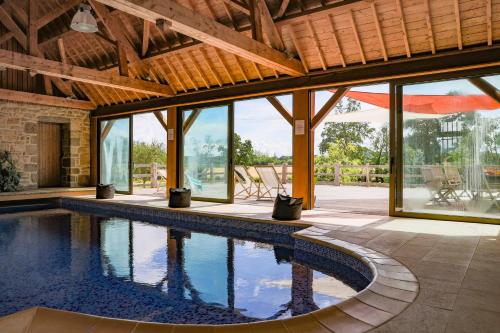 einen Innenpool in einem Haus mit Fenstern in der Unterkunft Manoir avec Piscine et Jacuzzi en Suisse Normande in La Carneille
