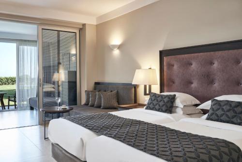 a hotel room with two beds and a living room at Atlantica Belvedere Resort - Adults Only in Kardamaina