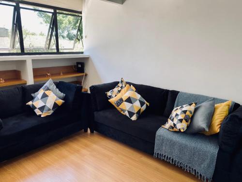 a living room with a black couch with pillows at Apartamento amplo a 4km do aeroporto internacional de Guarulhos Cecap in Guarulhos