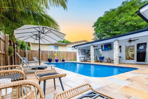 a swimming pool with a table and chairs and an umbrella at Casa Tropicana - Heated Pool, Game Room & Mins from beach in Hallandale Beach