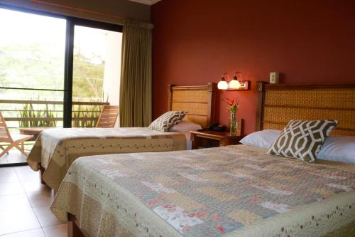 a hotel room with two beds and a balcony at Hotel Ladera in Boquete