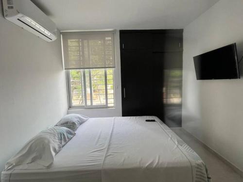 ein weißes Bett in einem Zimmer mit Fenster in der Unterkunft apartaestudió dúplex Neiva in Neiva