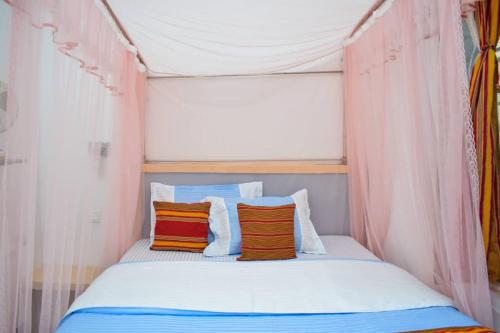 a bed in a tent with two pillows on it at Citizen Cafe & Chambers in Mbale