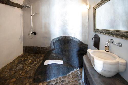 a bathroom with a sink and a bath tub at Ducato di Oia - Adults Only in Oia