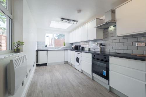 a kitchen with white cabinets and a washer and dryer at (S4) Beautiful Studio Close To a Tube Station in Harrow on the Hill