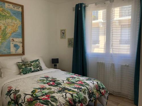 a bedroom with a bed with a flowered blanket and a window at Cannes centre-deux pièces-tout confort in Cannes