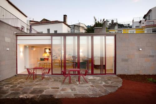 a glass extension of a house with chairs and tables at AngrA + in Angra do Heroísmo
