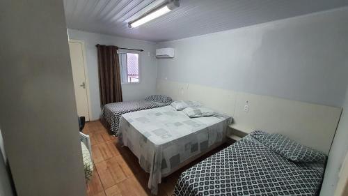 a room with two beds in a room with a window at Hotel Majestic in Pelotas