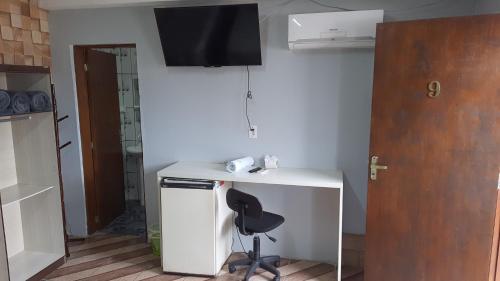 Habitación con escritorio con silla y TV en la pared. en Hotel Majestic, en Pelotas