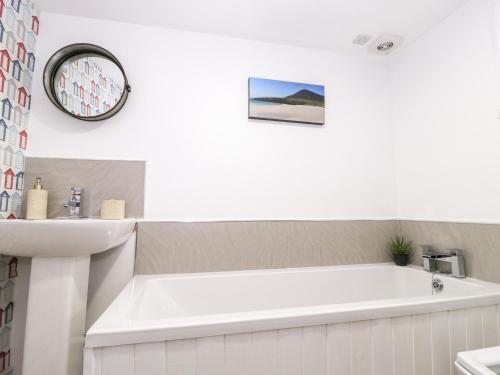 Baño blanco con bañera y lavamanos en Beech Cottage, en Lochs