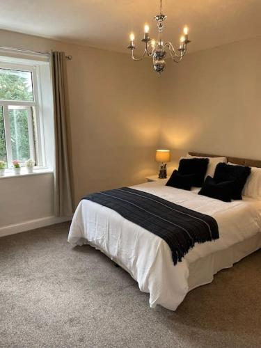 a bedroom with a large bed and a chandelier at Hawksworth Cottage - Grassington Village Location in Grassington