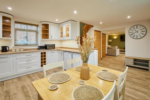 a kitchen with a table and chairs and a clock on the wall at Host & Stay - Fawcett Cottage in Tollerton