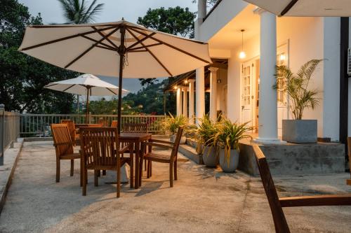 een tafel en stoelen met een parasol op een patio bij Kingsman House in Kandy